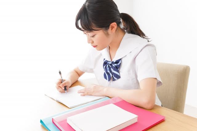 机に向かい勉強をしている女子生徒