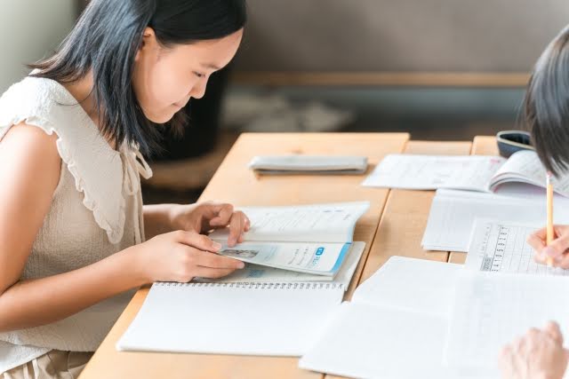 2人の学生がテキストを広げて勉強しています